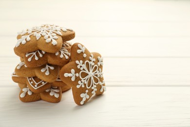 Tasty Christmas cookies with icing on white wooden table. Space for text