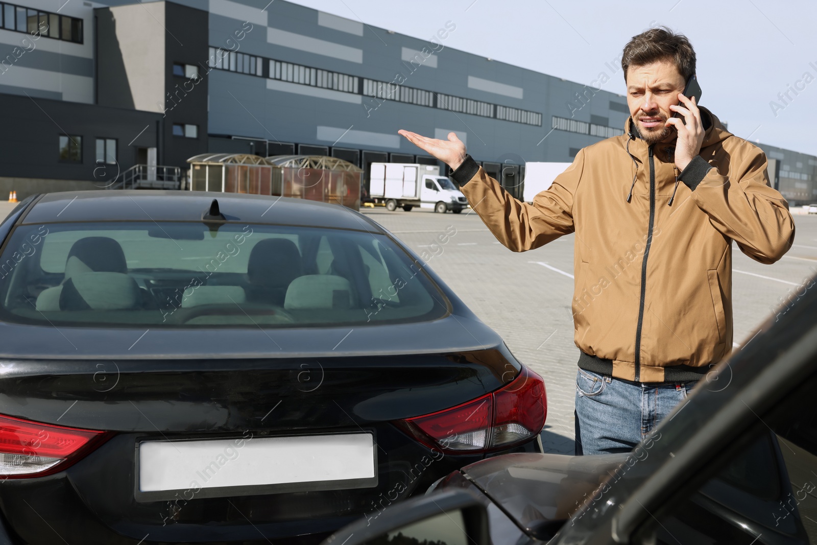 Photo of Man talking on phone near car with scratch outdoors Auto accident