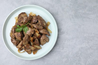 Tasty fried chicken liver with onion and parsley on grey table, top view. Space for text