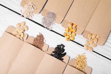 Photo of Many different vegetable seeds on white wooden table, flat lay