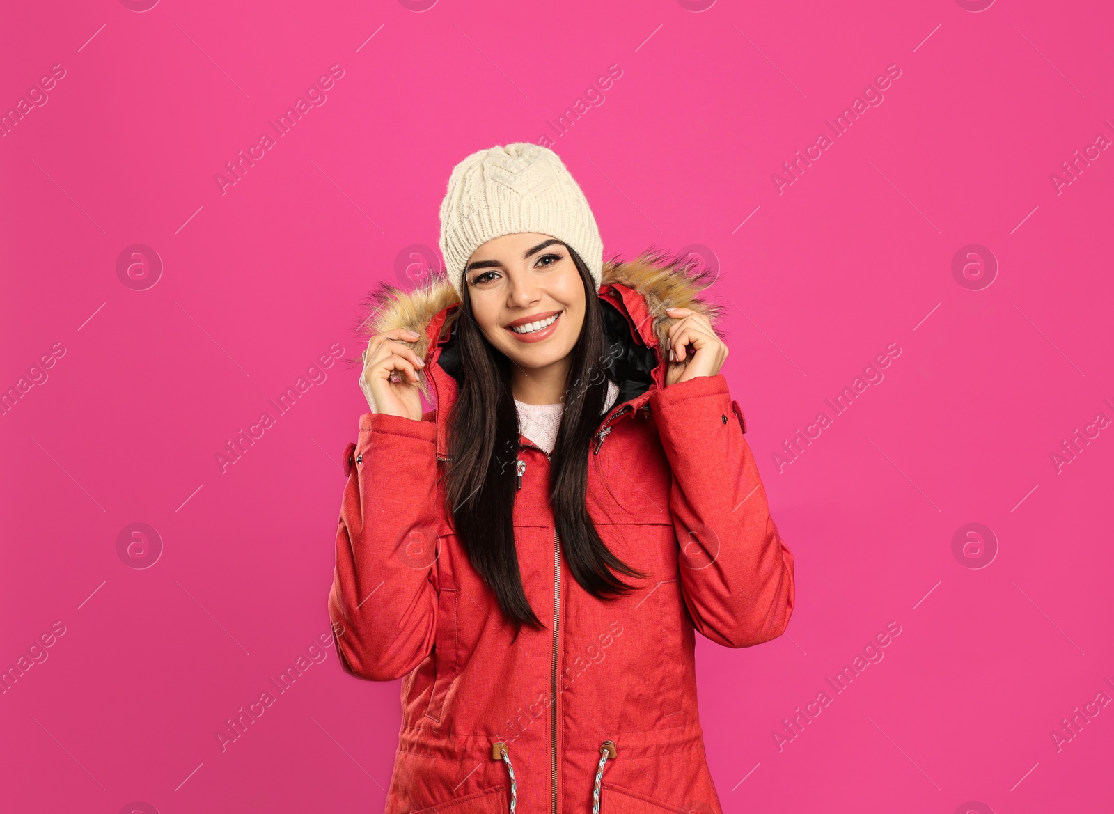 Photo of Happy young woman in warm clothes on pink background. Winter vacation
