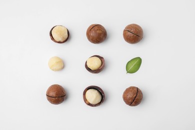 Photo of Tasty Macadamia nuts and green leaf on white background, flat lay