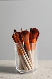 Photo of Set of professional makeup brushes on table against grey background