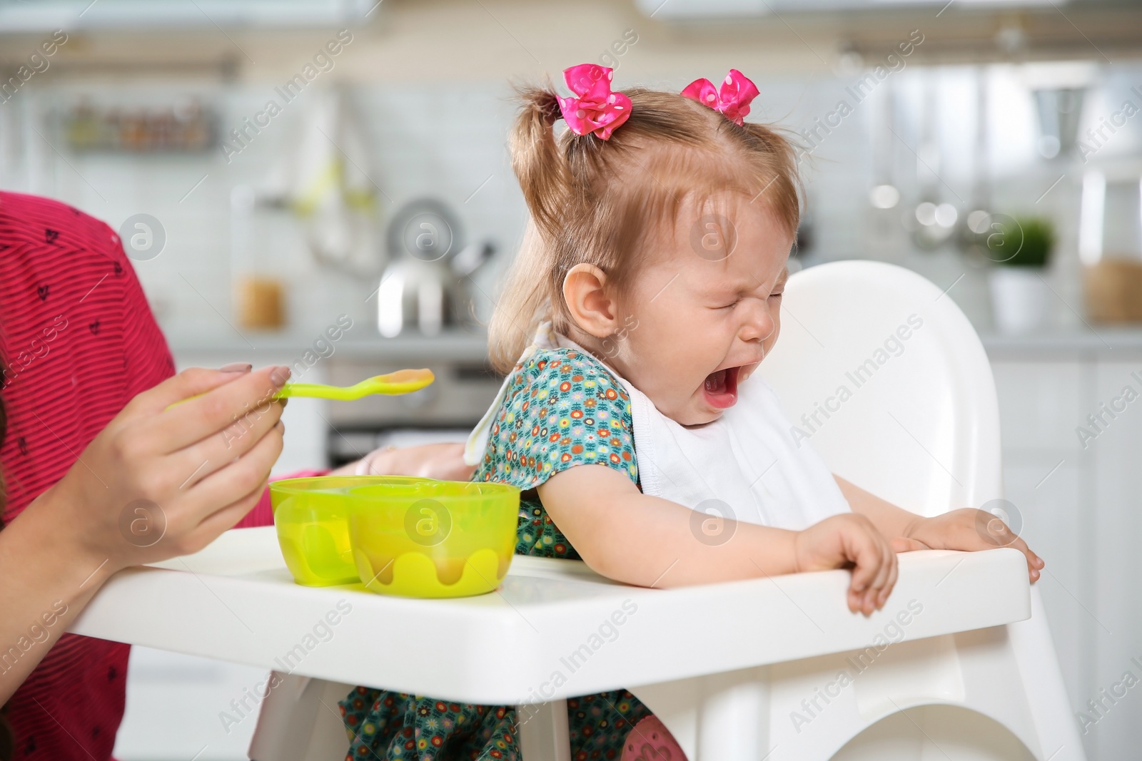 Photo of Mother feeding her little baby with healthy food in kitchen