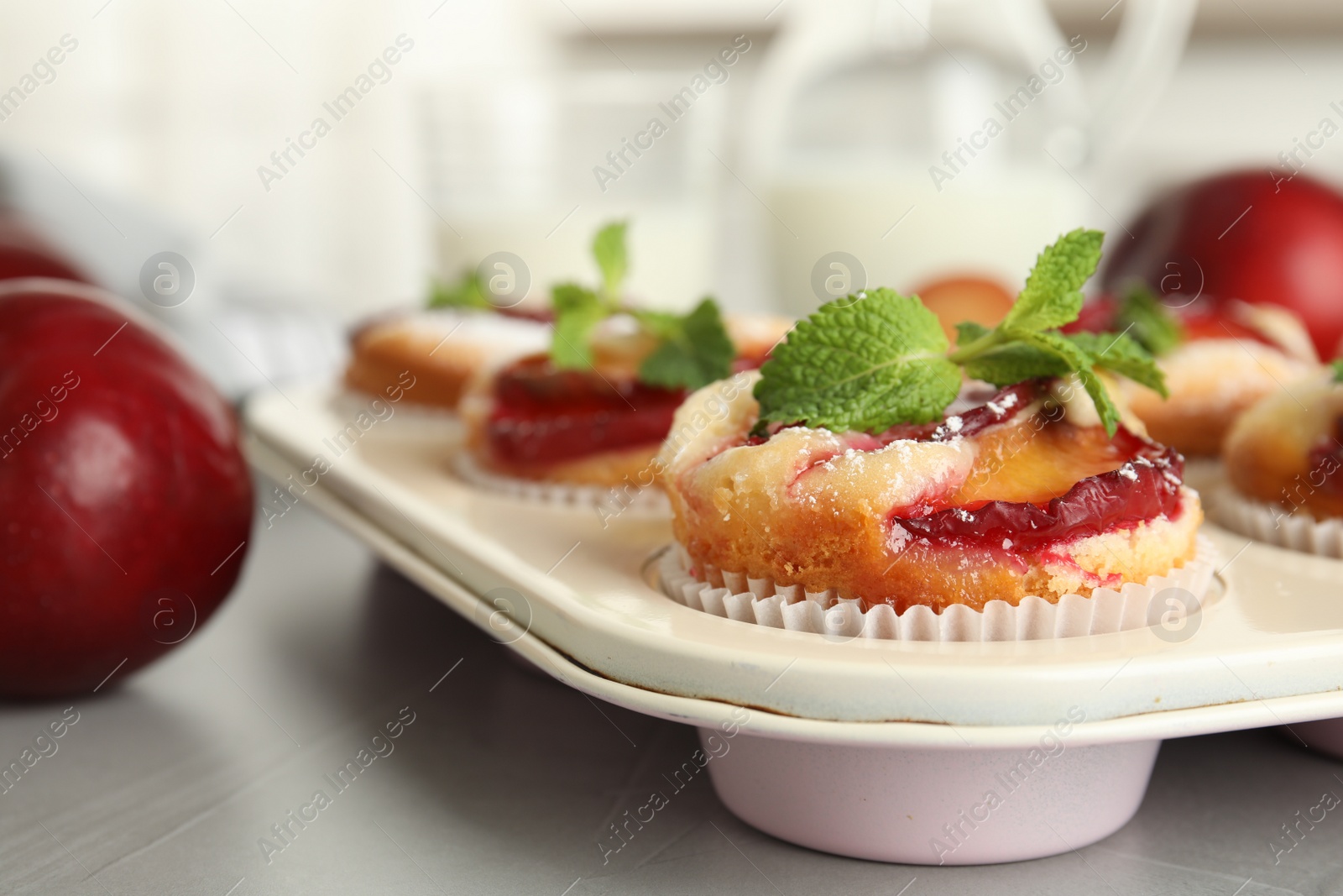 Photo of Delicious cupcakes with plums in baking pan, closeup