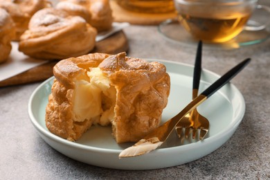 Photo of Delicious profiterole filled with cream on grey table, closeup