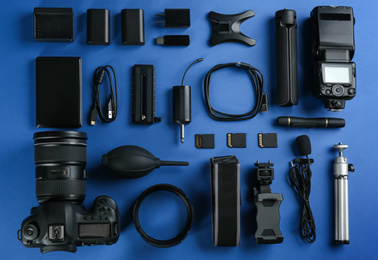 Photo of Flat lay composition with camera and video production equipment on blue background