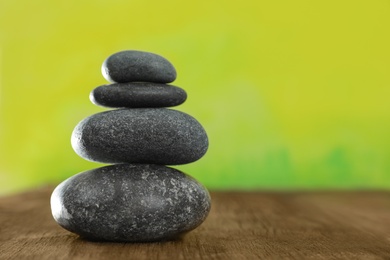 Photo of Stack of stones on table against blurred green background, space for text. Zen concept