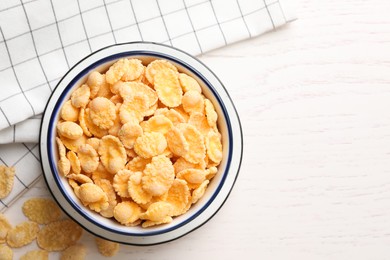 Photo of Bowl of tasty corn flakes on white wooden table, flat lay. Space for text
