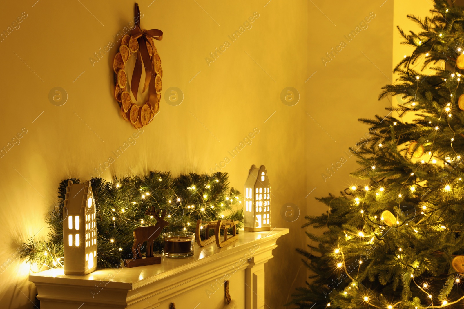 Photo of Fireplace with Christmas accessories and decorative wreath near fir tree in room