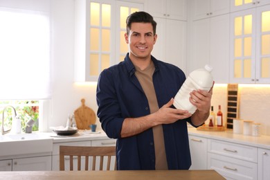 Man with gallon bottle of milk at wooden table in kitchen