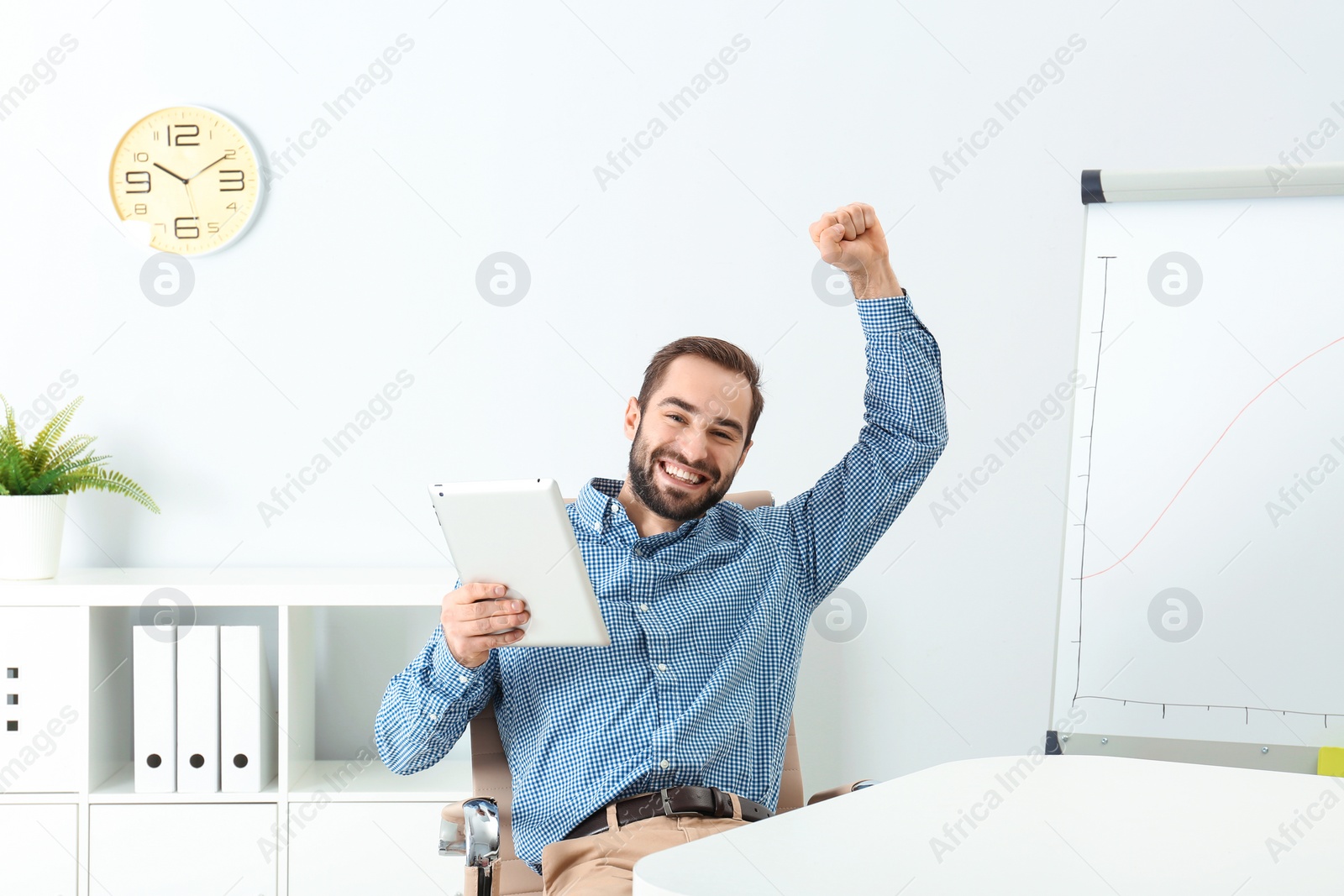 Photo of Emotional young man with tablet celebrating victory in office