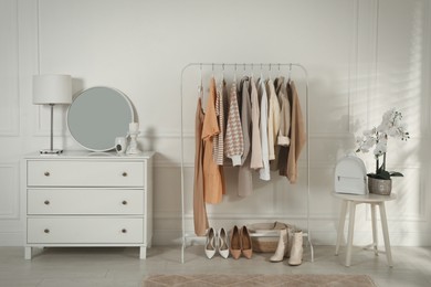 Modern dressing room interior with stylish clothes, shoes and beautiful orchid flowers