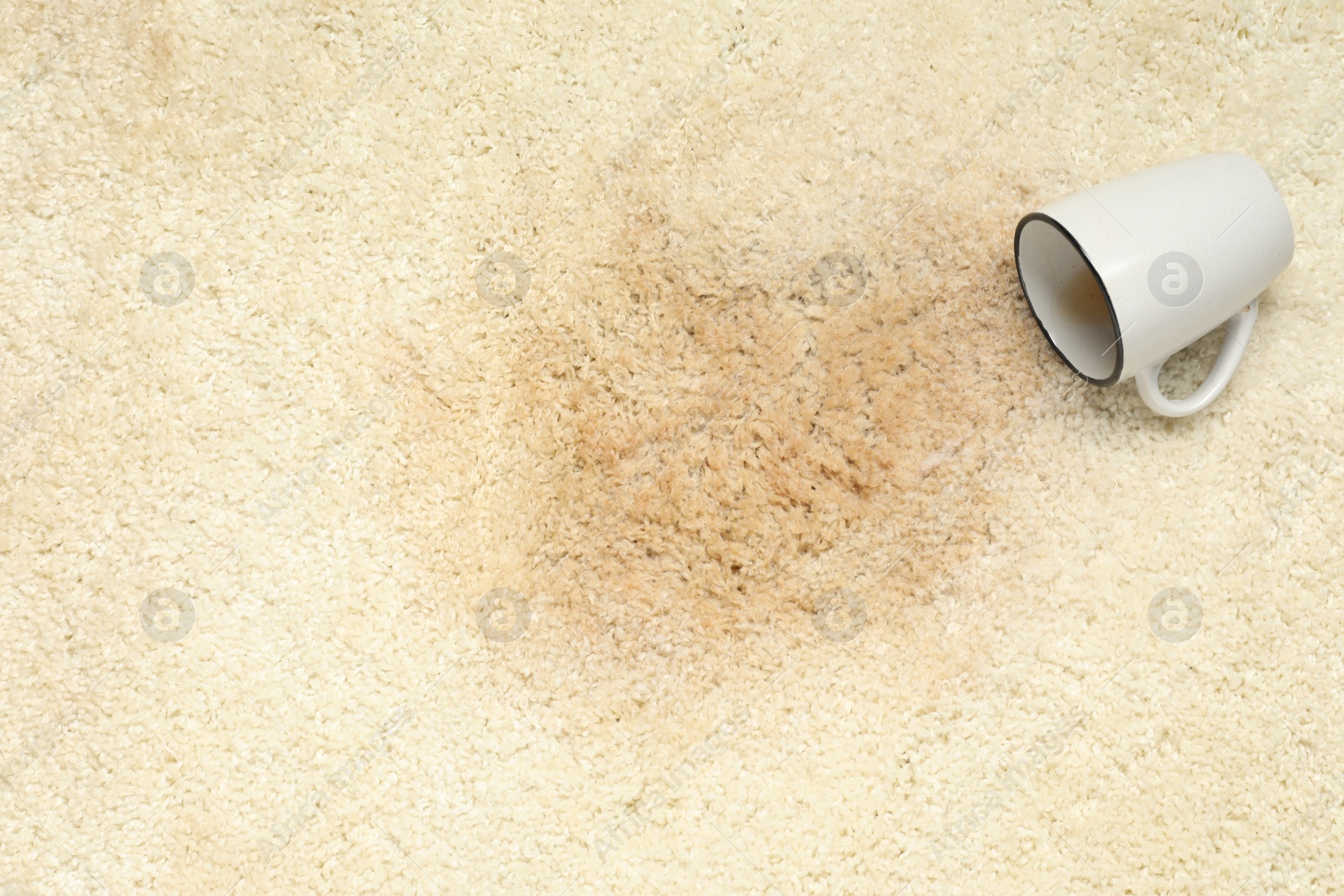 Photo of Overturned cup and spilled drink on beige carpet, top view. Space for text