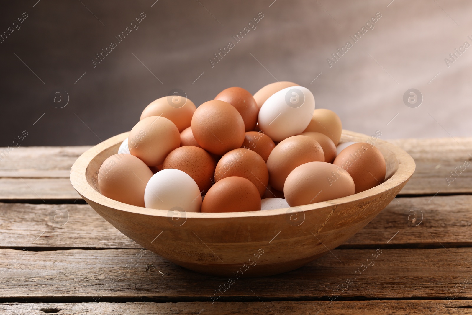 Photo of Fresh chicken eggs in bowl on wooden table