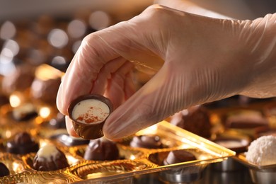 Photo of Woman packing delicious candies at production line, closeup