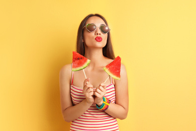 Beautiful young woman posing with watermelon on color background