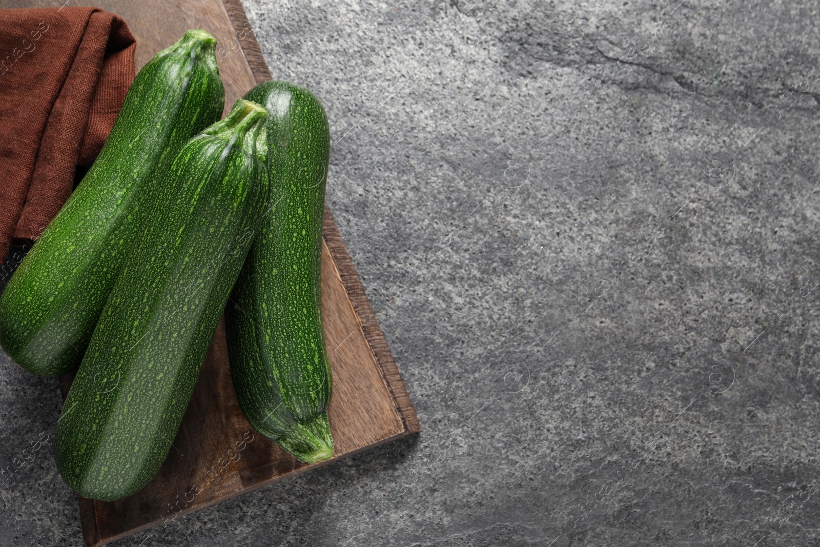 Photo of Raw ripe zucchinis on grey table, top view. Space for text