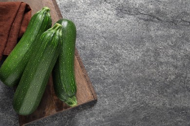 Photo of Raw ripe zucchinis on grey table, top view. Space for text