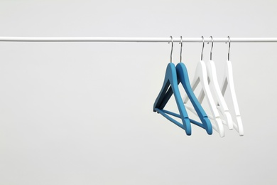 Photo of Empty clothes hangers on metal rail against light background. Space for text