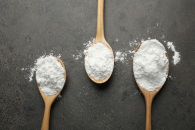 Photo of Baking powder in spoons on grey textured table, flat lay