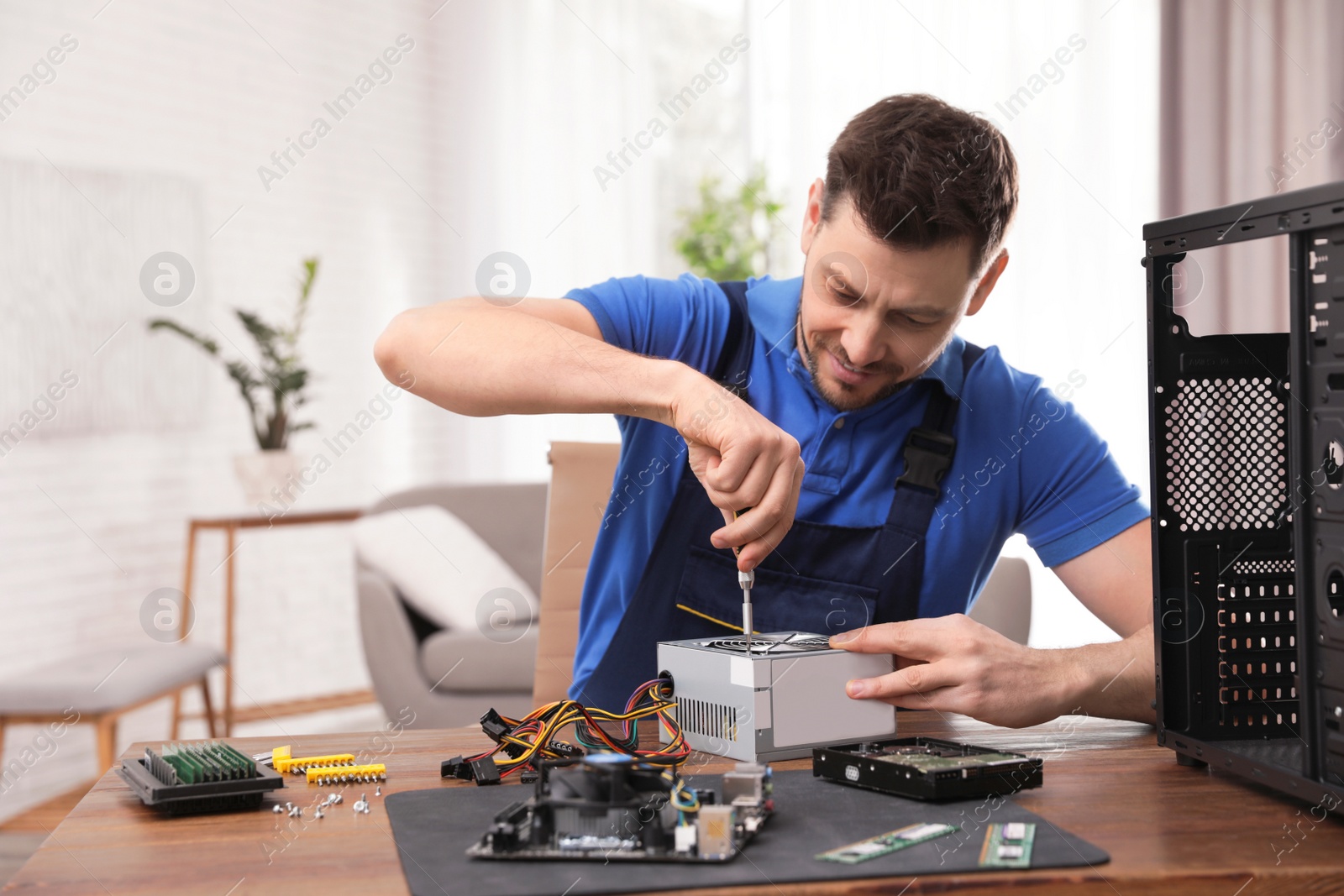 Photo of Male technician repairing power supply unit at table indoors