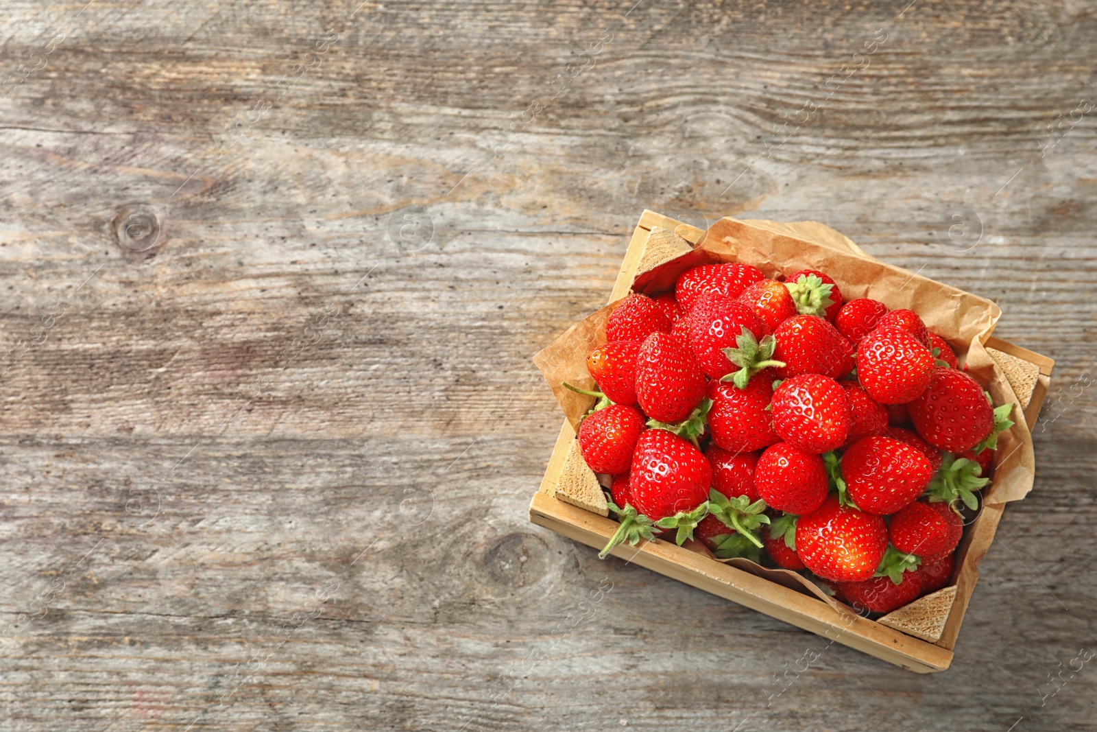 Photo of Crate with ripe strawberries on wooden background, top view