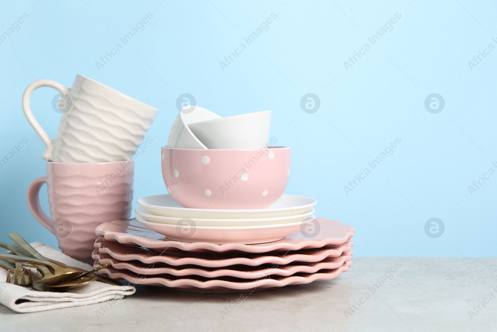 Photo of Beautiful ceramic dishware, cups and cutlery on light grey table, space for text