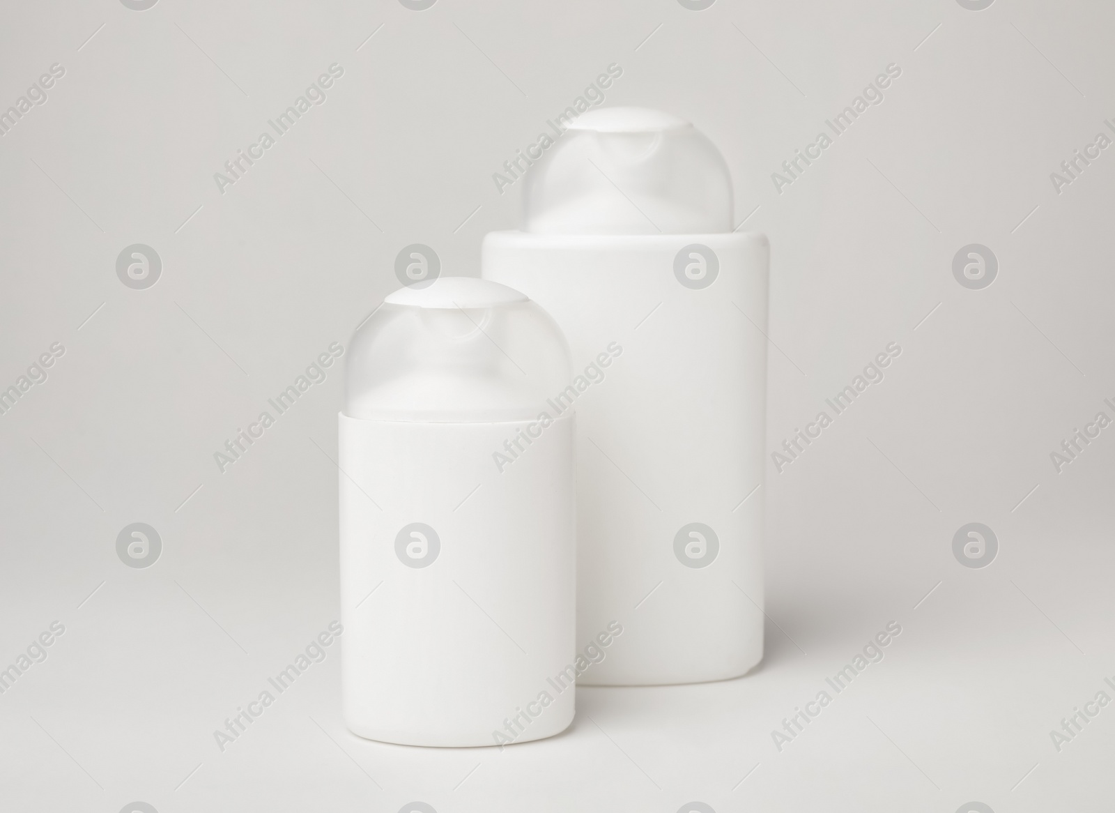 Photo of Bottles of cosmetic products on light background