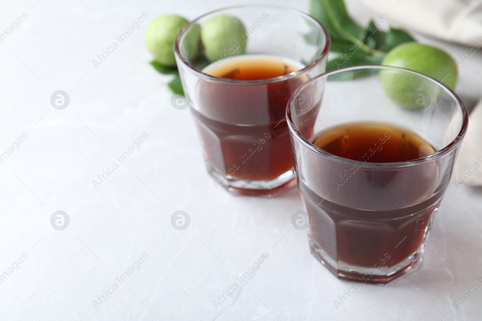 Photo of Delicious liqueur and fresh walnuts on light table, closeup. Space for text