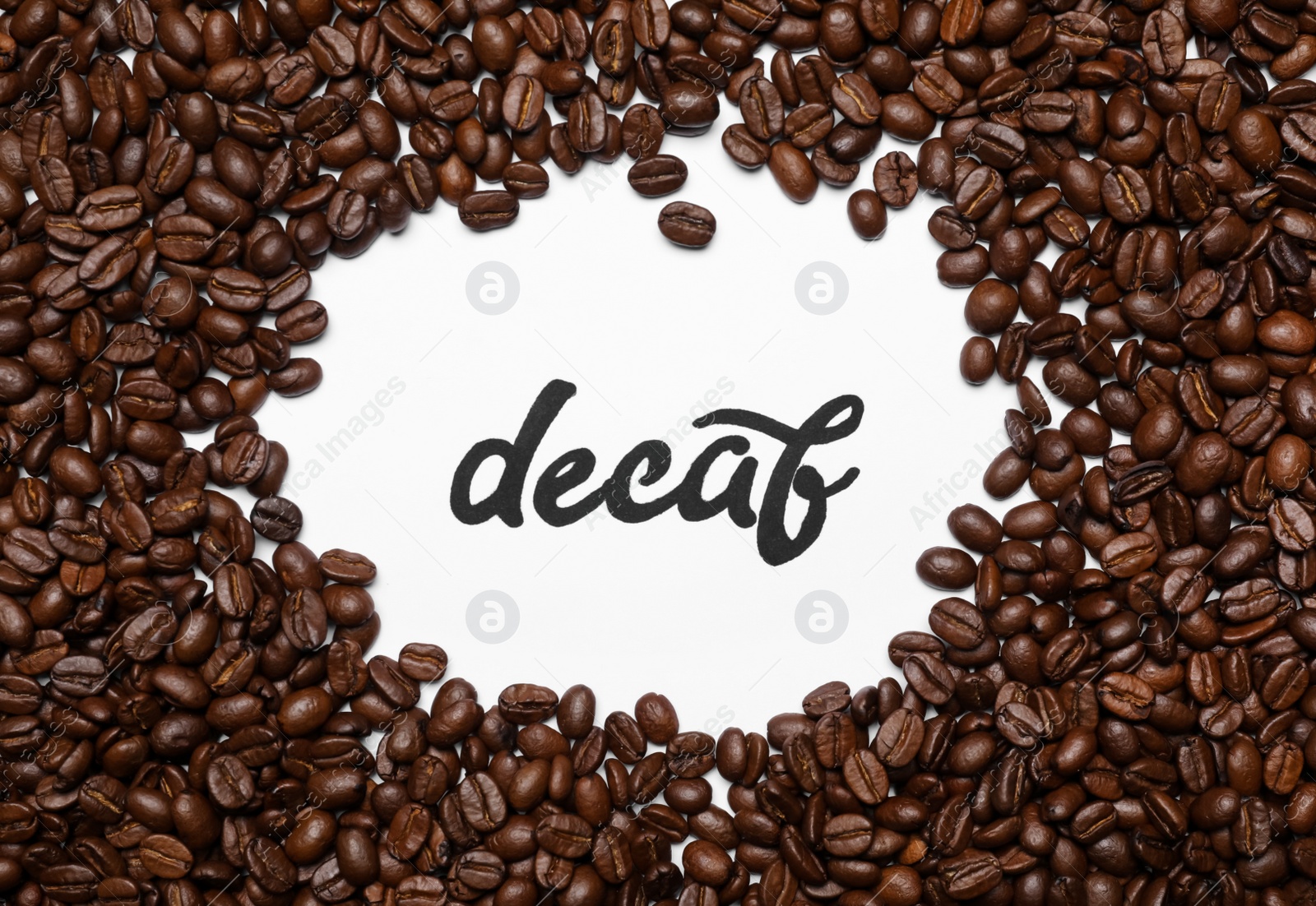 Photo of Word Decaf and coffee beans on white background, top view