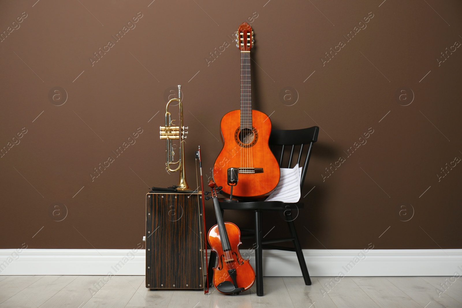 Photo of Set of different musical instruments near brown wall indoors