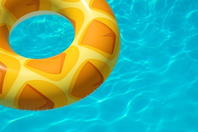 Photo of Bright inflatable ring floating in swimming pool on sunny day. Space for text