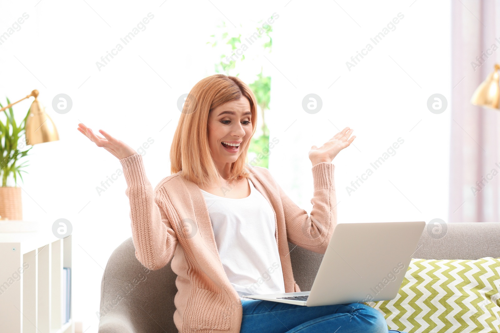 Photo of Woman using laptop for video chat in living room