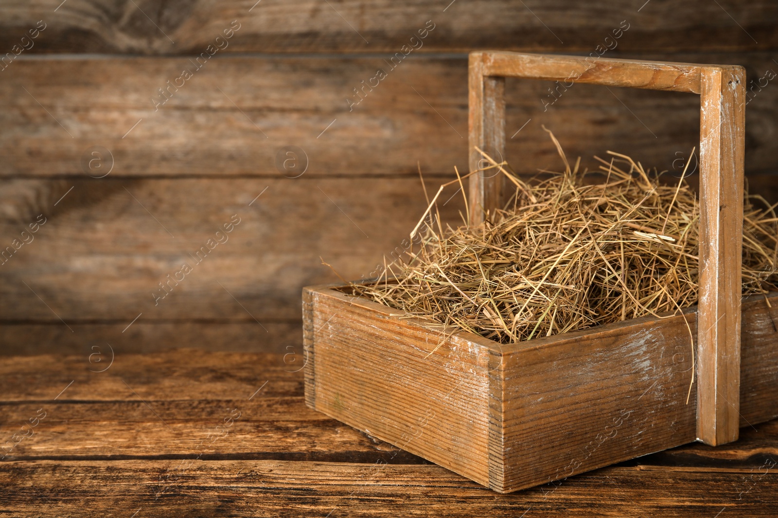 Photo of Dried hay in crate on wooden table. Space for text