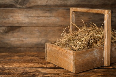 Photo of Dried hay in crate on wooden table. Space for text