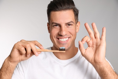 Photo of Man holding toothbrush with paste on light background