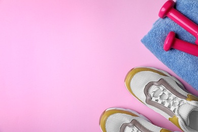 Flat lay composition with dumbbells, sneakers, towel and space for text on color background. Home fitness