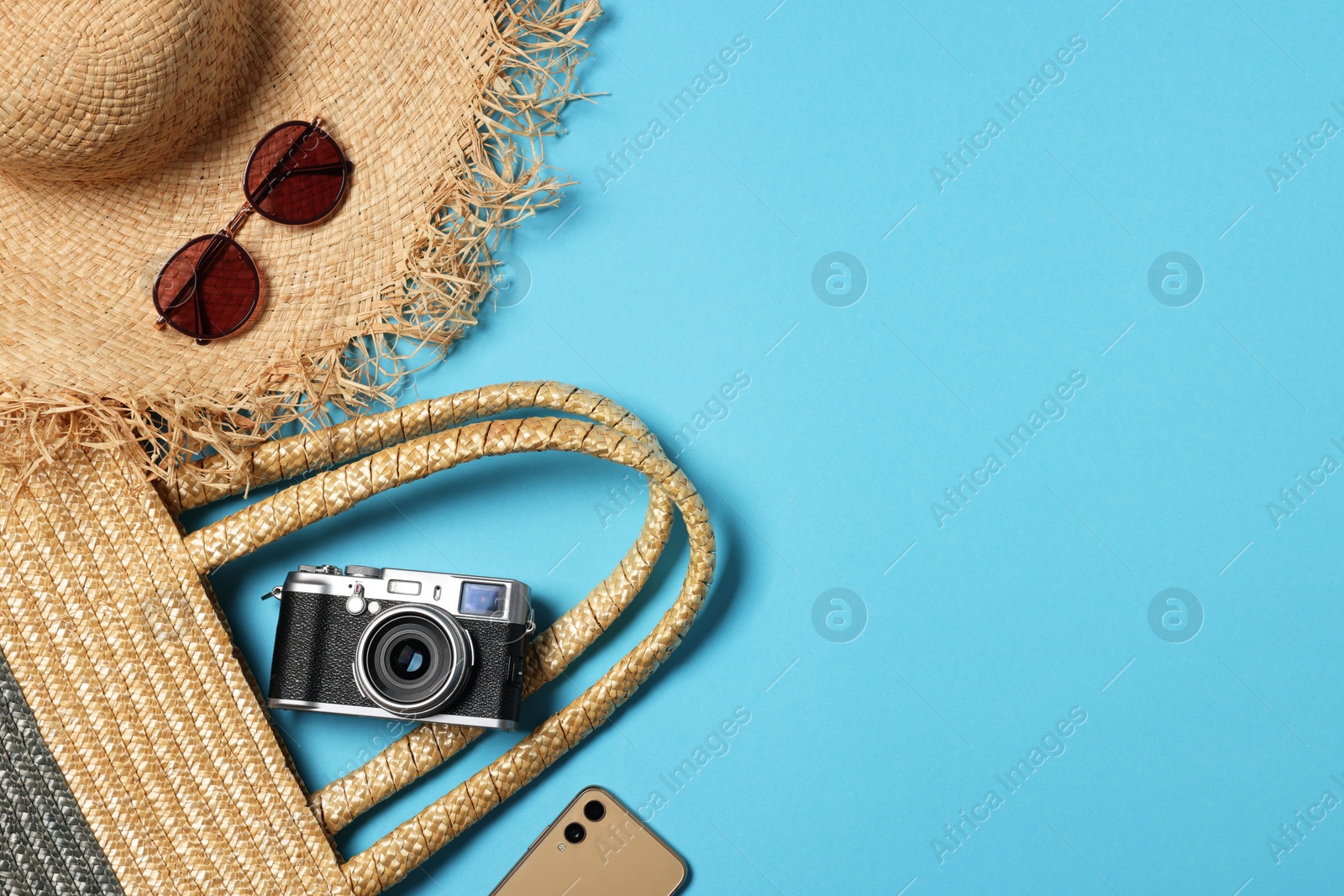 Photo of Flat lay composition with wicker bag and other beach accessories on light blue background. Space for text