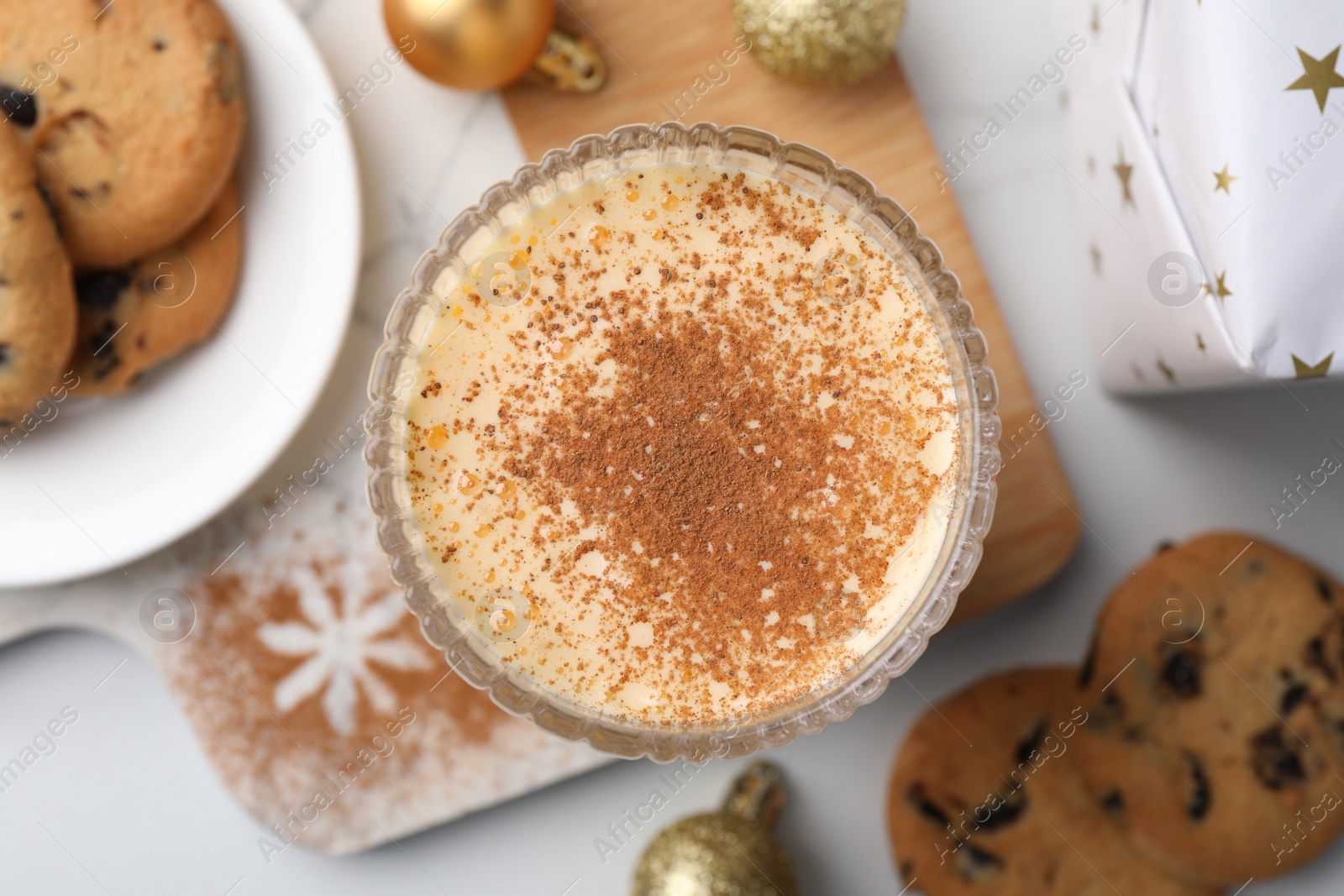 Photo of Glass of delicious eggnog with cinnamon on white table, flat lay