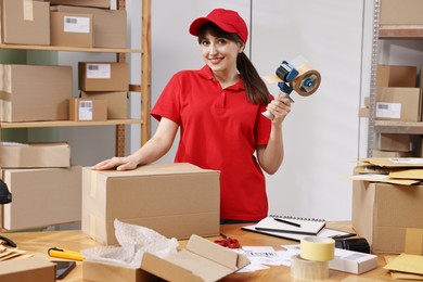 Parcel packing. Post office worker with tape dispenser and box at wooden table indoors