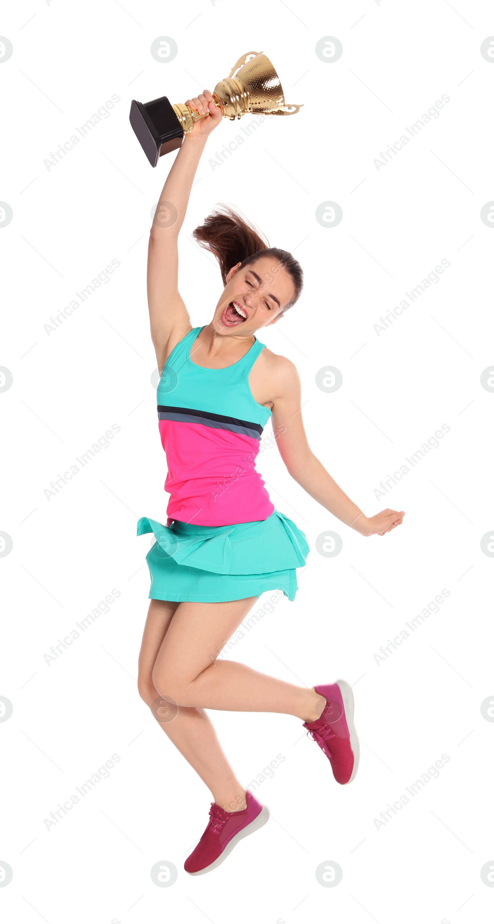 Photo of Happy young woman in tennis dress jumping with gold trophy cup on white background