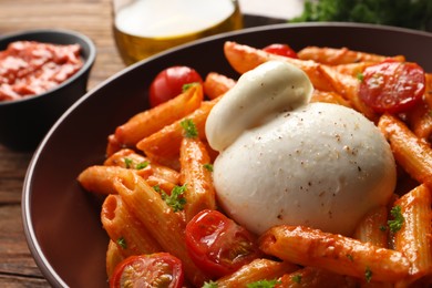 Delicious pasta with burrata cheese and tomatoes on table, closeup