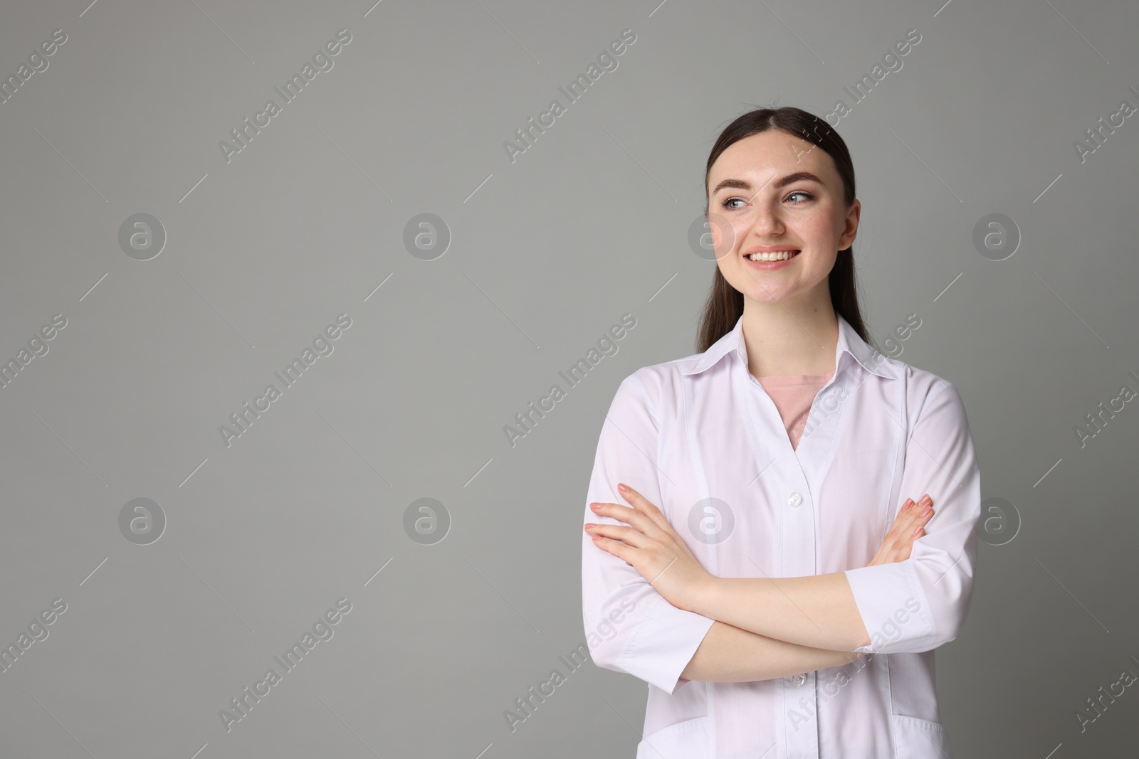 Photo of Cosmetologist in medical uniform on grey background, space for text