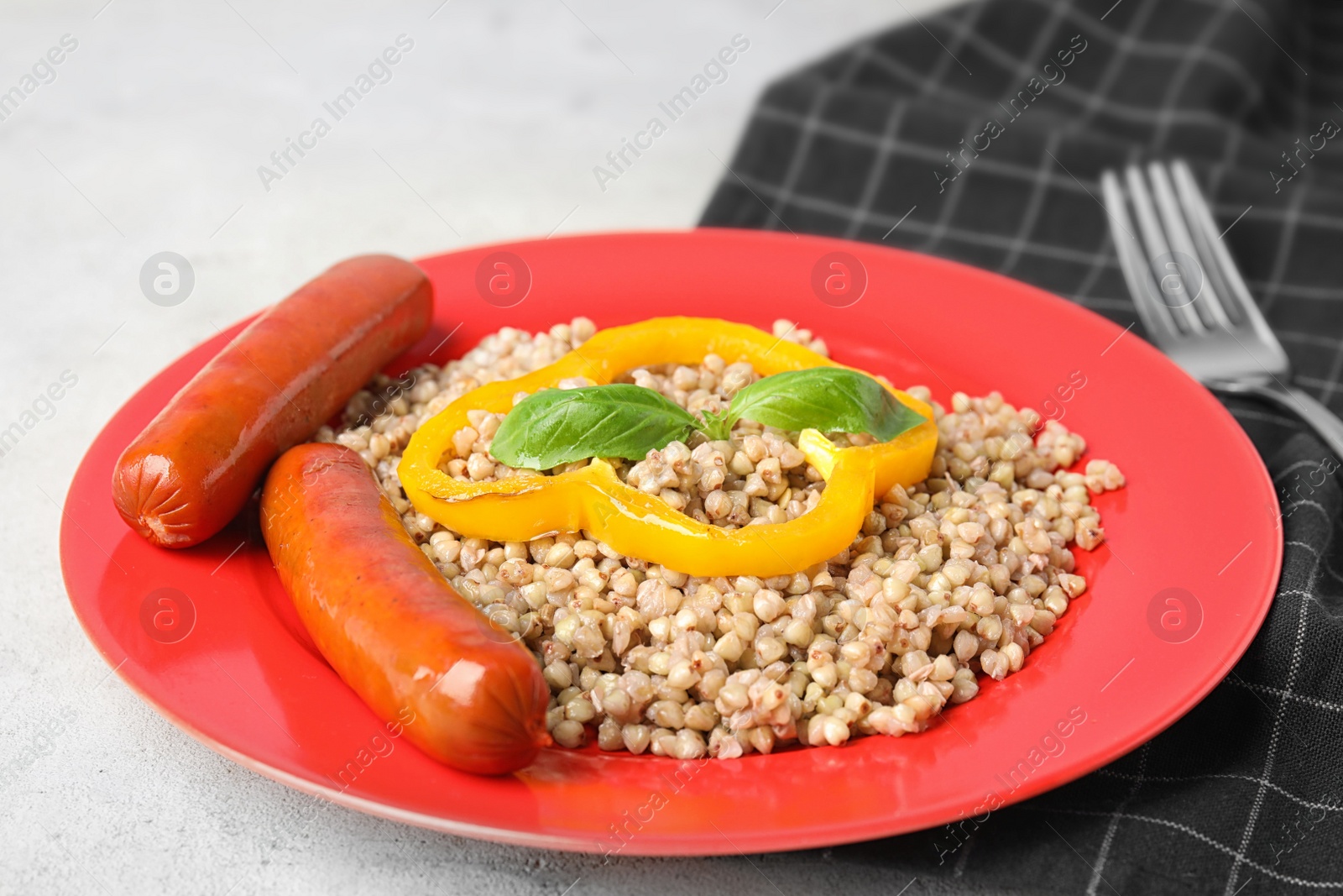 Photo of Tasty buckwheat porridge with sausages on light table, closeup