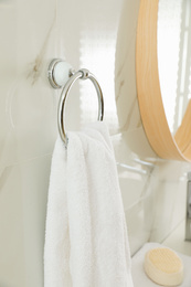 Holder with clean towel on light wall in bathroom