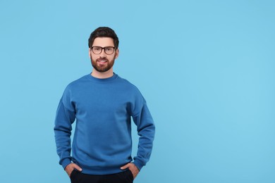 Portrait of handsome man in glasses on light blue background, space for text