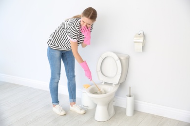 Photo of Woman cleaning toilet bowl in bathroom