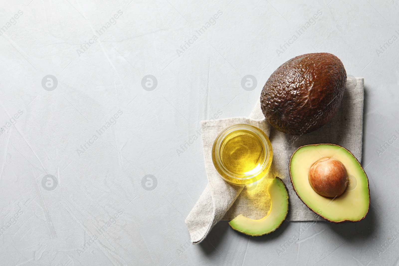 Photo of Jar with oil and ripe fresh avocados on table, top view