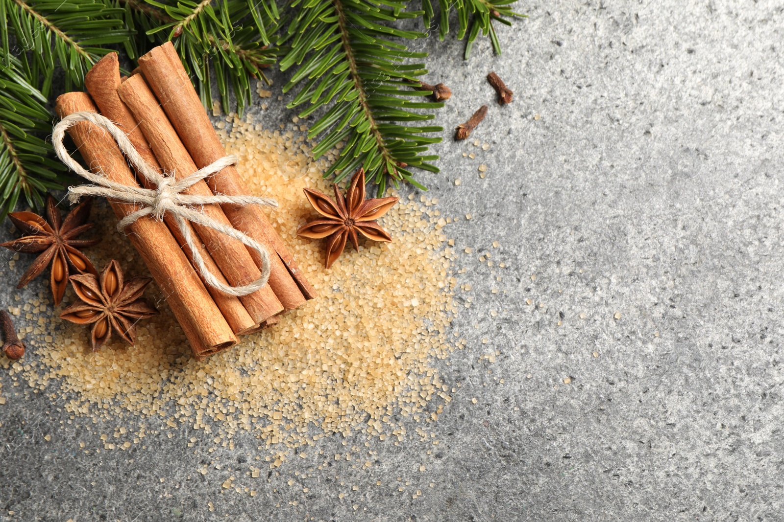 Photo of Different spices and fir branches on gray table, flat lay. Space for text